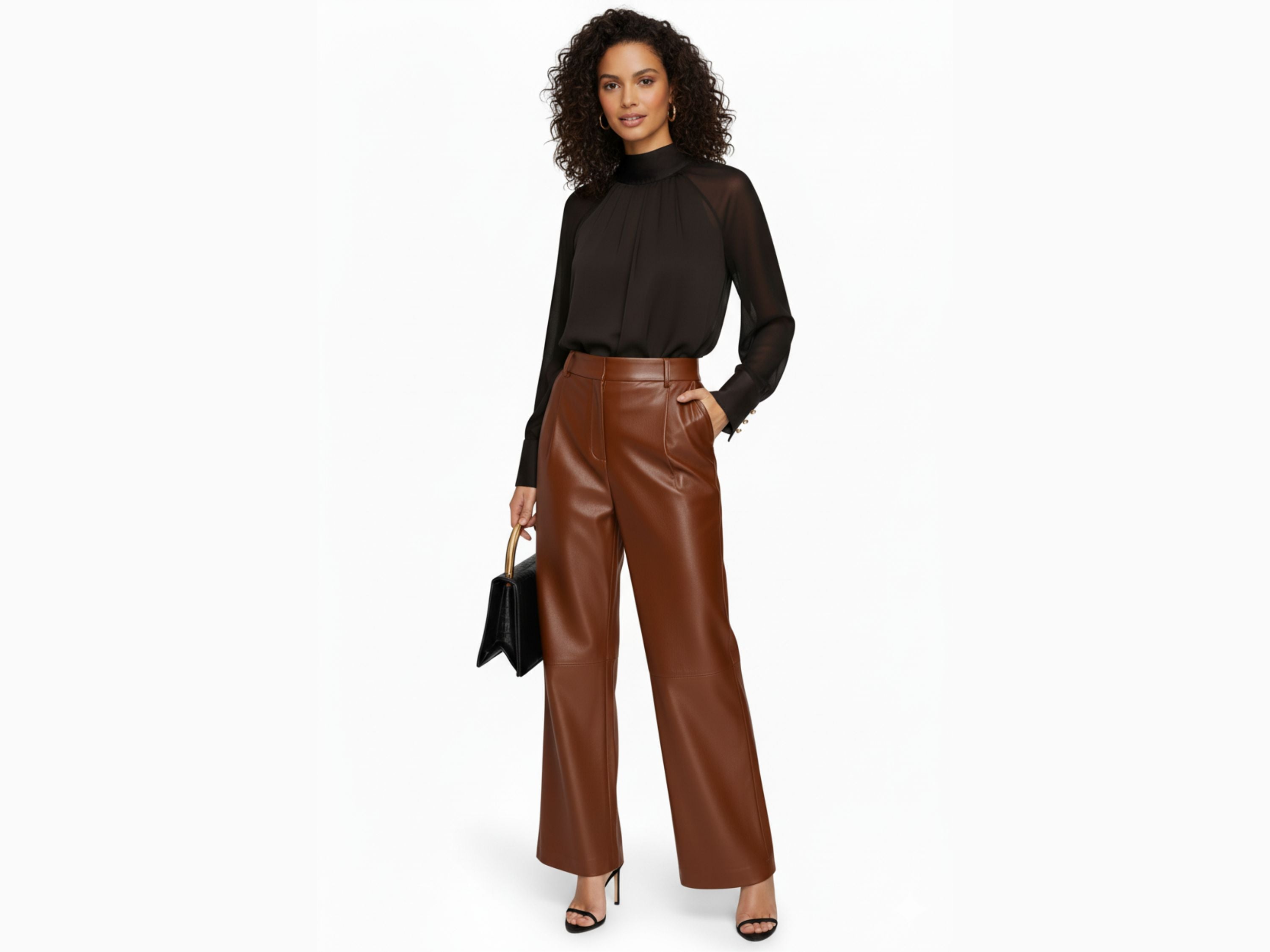 Woman wearing a black sheer top and brown leather pants on a white background